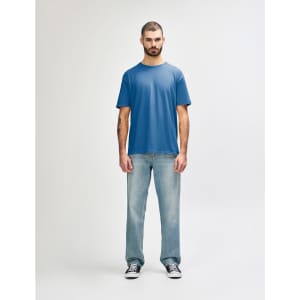 A model wearing a blue Gildan Softstyle adult T-shirt and light blue jeans, standing against a plain background.