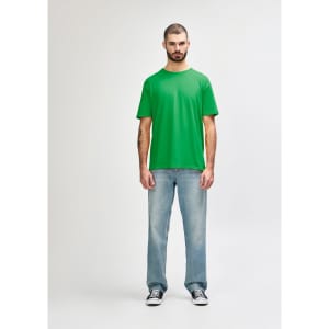 A green Gildan Softstyle adult T-shirt displayed on a model, paired with blue jeans and white shoes.