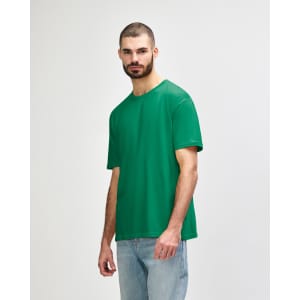 A green Gildan Softstyle adult t-shirt displayed on a model, featuring a simple design and loose fit.