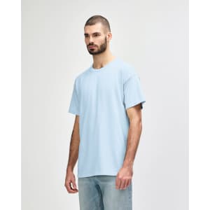 A softstyle adult t-shirt in light blue displayed on a model, featuring a round neck and short sleeves. It has a logo.