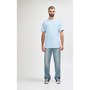 A plain light blue Gildan Softstyle adult T-shirt worn with straight-leg jeans and white shoes, featuring a logo.