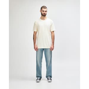 A white Gildan Softstyle adult T-shirt displayed on a model, paired with light blue jeans. The model stands against a neutral background.