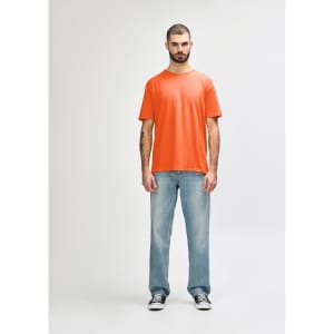 An orange Gildan Softstyle adult T-shirt worn by a man, paired with light blue jeans and white shoes.