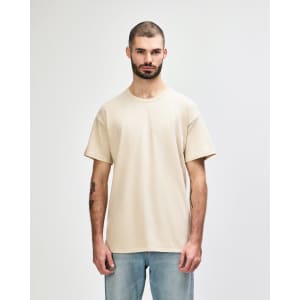A beige adult t-shirt is displayed worn by a male model, featuring a simple design and short sleeves.