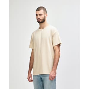A lightweight, cream-coloured adult t-shirt displayed on a model, featuring a relaxed fit and simple design.