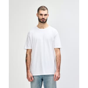 A plain white adult t-shirt is displayed on a model. The t-shirt features a logo and has a relaxed fit.