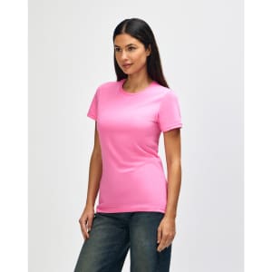 A pink Gildan Softstyle ladies' T-shirt is displayed on a model, styled with denim jeans. The shirt features a logo.