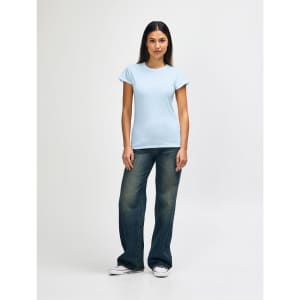 A light blue ladies' t-shirt paired with blue jeans and white sneakers, featuring a brand logo.