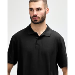 A black Gildan Softstyle adult double pique polo featuring a collared neckline and three buttons. It has a logo on the fabric.
