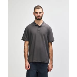 A grey Gildan Softstyle adult double pique polo shirt on a model, featuring a collar and short sleeves.