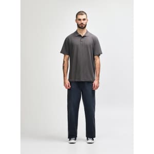A grey Gildan Softstyle Adult Double Pique Polo is worn by a model, paired with light blue jeans. The polo features a logo.