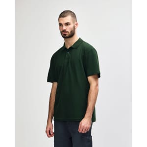 A model wearing a dark green polo shirt with a classic collar and short sleeves, featuring a logo.