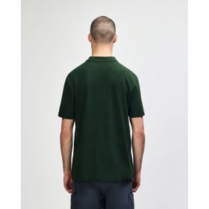 A green Gildan Softstyle adult double pique polo shirt is displayed from the back, featuring short sleeves.