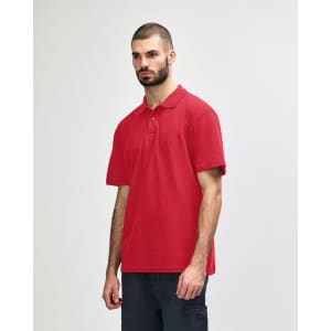 A red Gildan Softstyle adult double pique polo, featuring a collar and short sleeves. The model stands against a neutral background.