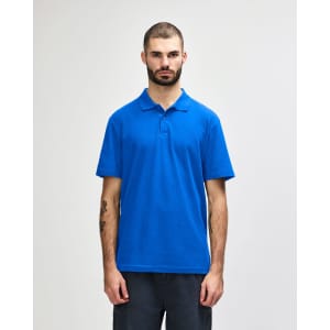 A plain blue Gildan Softstyle adult double pique polo worn by a standing male model with short hair.