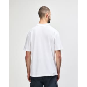 A white Gildan Softstyle adult double pique polo shirt displayed on a model from the back, featuring a small logo.
