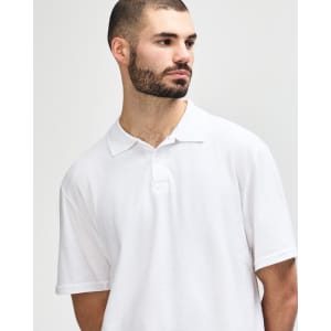 A white Gildan Softstyle adult double pique polo shirt on a model, featuring a collar and three buttons.