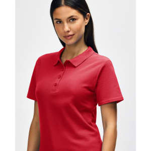 A woman is wearing a red Gildan Softstyle ladies' double pique polo, featuring a classic collar and buttons.