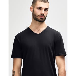 A black Gildan Softstyle adult v-neck t-shirt worn by a model standing with hands behind their back.