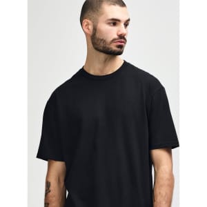 A black Gildan Softstyle adult midweight T-shirt displayed on a model, featuring a simple design and relaxed fit.