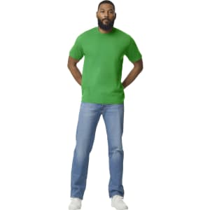 A green Gildan Softstyle adult midweight T-shirt displayed on a male model, paired with blue jeans and white shoes.