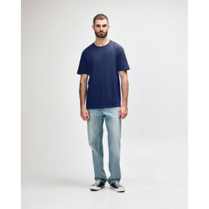 A man wearing a navy Gildan Softstyle adult midweight T-shirt and light blue jeans, standing against a plain background.