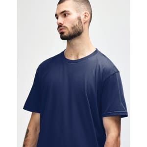 A model wearing a navy blue Gildan Softstyle Adult Midweight T-Shirt. The shirt has a round neckline and short sleeves.