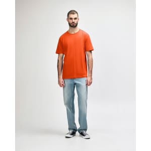 An orange Gildan Softstyle adult midweight T-shirt worn by a model with denim jeans and white shoes.