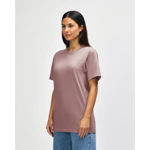 A midweight adult t-shirt in a muted pink colour, featuring a crew neckline and short sleeves. The model stands against a plain background.
