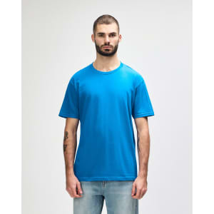 A model wearing a bright blue Gildan Softstyle adult midweight t-shirt, featuring a simple design and a logo.