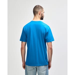 A blue midweight T-shirt viewed from the back, worn by a person with dark hair and casual pants.