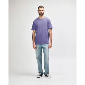 A model wearing a purple Gildan Softstyle Adult Midweight T-Shirt paired with black jeans and sneakers.