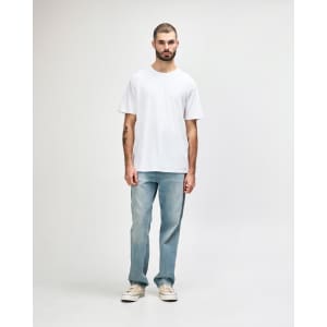 A model wears a white midweight T-shirt paired with black jeans and sneakers, featuring a logo on the shirt.