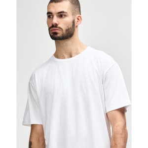 A model wearing a plain white Gildan Softstyle adult midweight T-shirt, featuring a simple design and a logo.