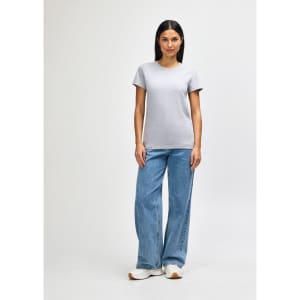 A grey midweight t-shirt on a model, paired with blue jeans and white shoes. The t-shirt has a logo.
