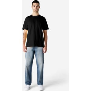 A black Gildan Softstyle adult t-shirt on a male model, paired with light blue jeans and white shoes.