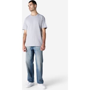 A grey adult T-shirt with a relaxed fit, paired with blue jeans and white shoes. The shirt features a logo.