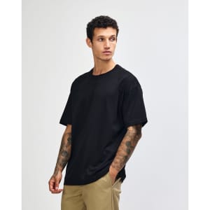 A model wearing a black American Apparel Super Heavyweight T-Shirt, paired with olive green cargo pants.
