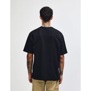 A black American Apparel Super Heavyweight T-Shirt viewed from the back, paired with olive green trousers.