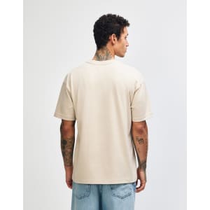 A light beige, unisex heavyweight t-shirt featuring a plain back design. It has a logo on the garment.