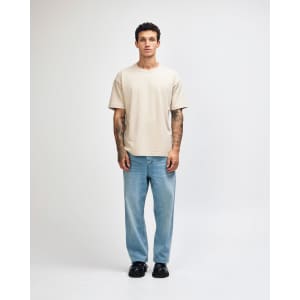 A light beige super heavyweight T-shirt worn by a male model, paired with light blue jeans and sneakers.