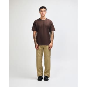 A model wears a brown American Apparel Super Heavyweight T-Shirt paired with olive green cargo pants and sneakers.