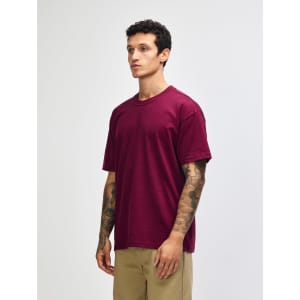 A maroon heavyweight t-shirt on a model, featuring a rounded neckline and short sleeves, with a logo present.
