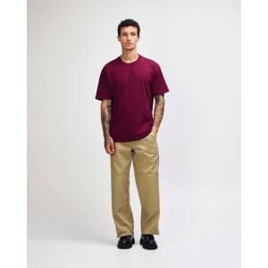A model wearing a maroon heavyweight T-shirt and olive green cargo pants, featuring a logo.