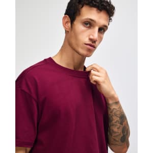 A maroon American Apparel Super Heavyweight T-Shirt displayed on a model with short hair and a neutral background.