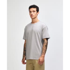 A grey super heavyweight T-shirt displayed on a model, featuring a simple design and straight fit.