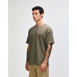 A green American Apparel super heavyweight t-shirt displayed on a model standing upright, featuring a round neckline.