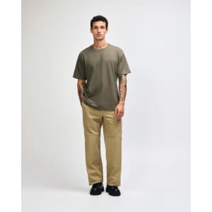 A model wearing an olive green American Apparel Super Heavyweight T-Shirt and matching cargo pants, paired with white sneakers.