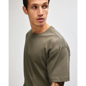 A model wearing an olive green American Apparel Super Heavyweight T-Shirt, featuring a simple design and crew neck.