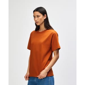 An orange Super Heavyweight T-Shirt displayed on a model, featuring a simple design and a branded logo.